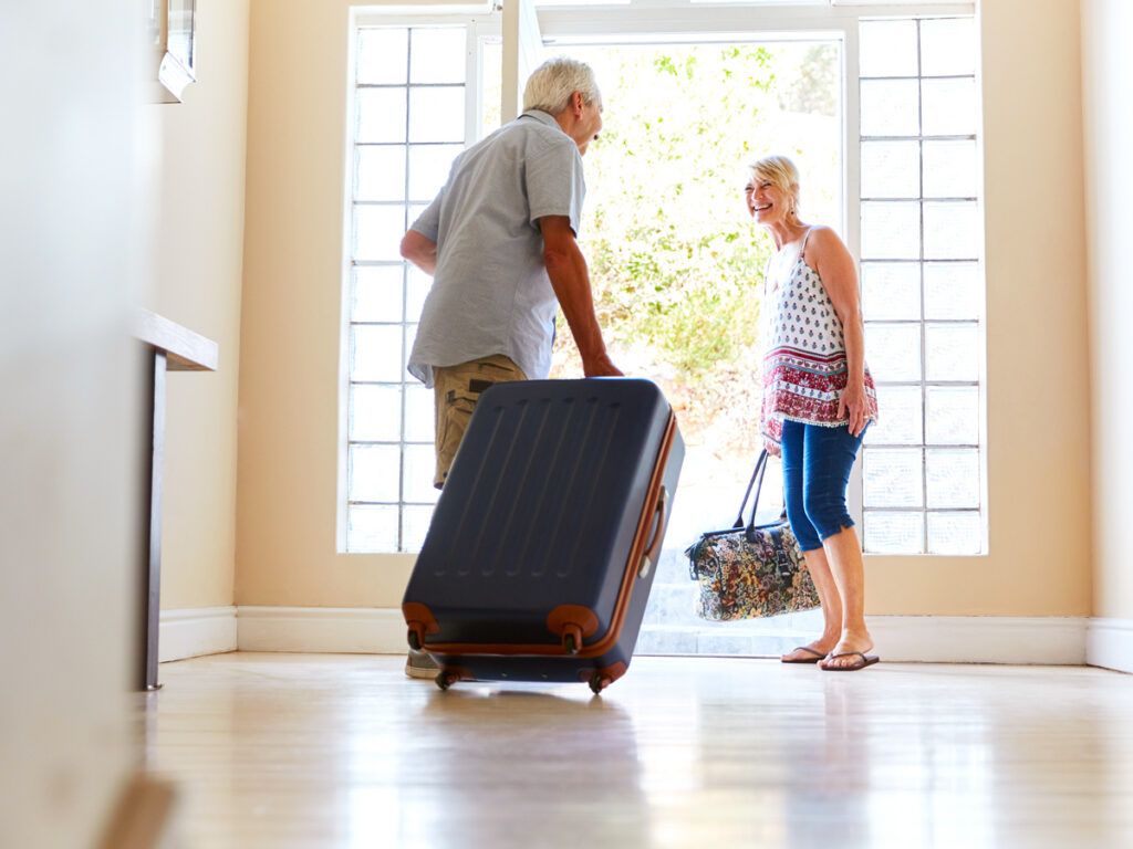 Couple walking out the door with luggage