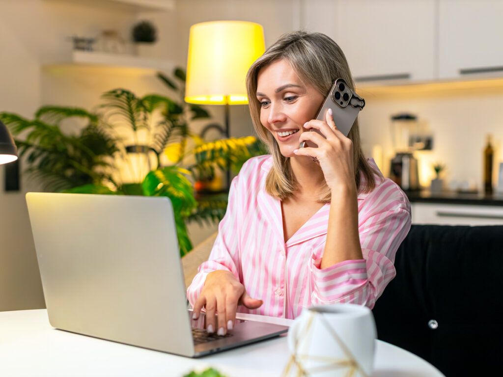 Woman talking on phone while using laptop computer