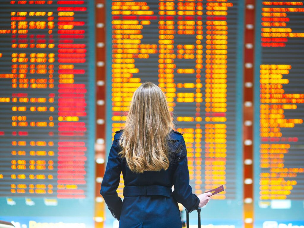 Traveler looking up at airport departures and arrivals board