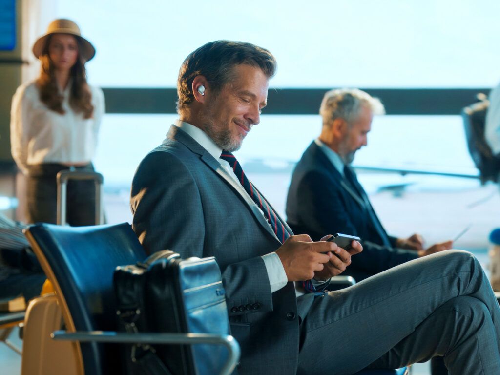 Man looking at phone while sitting at airport gate