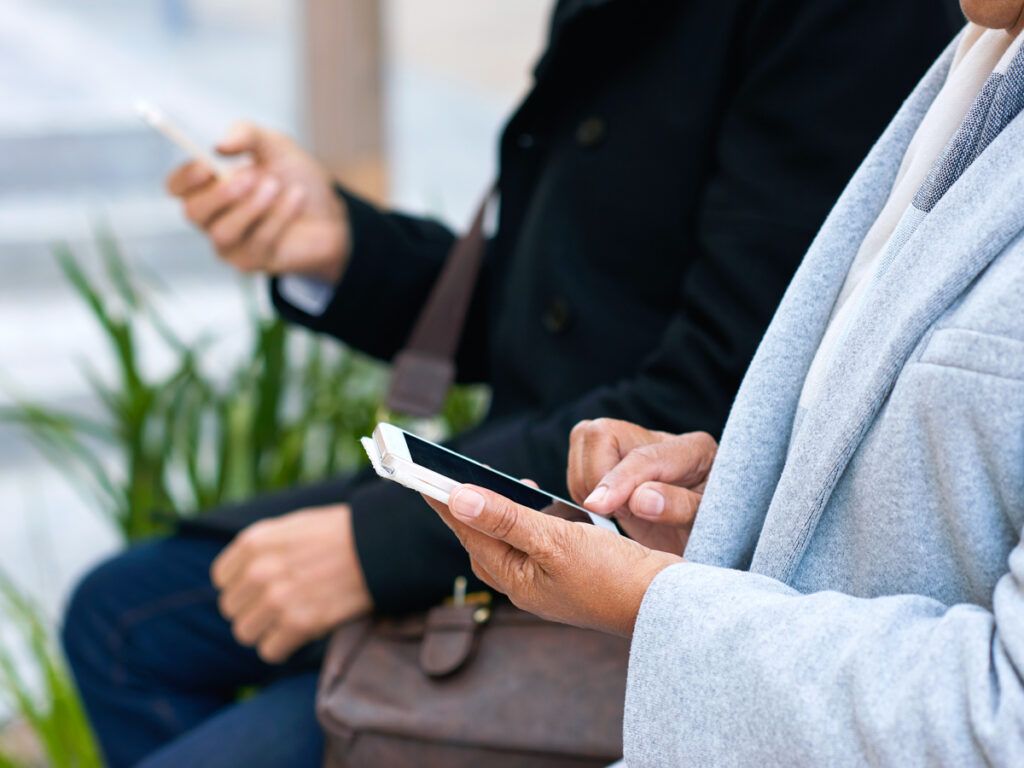 Two people sitting and looking at their phones