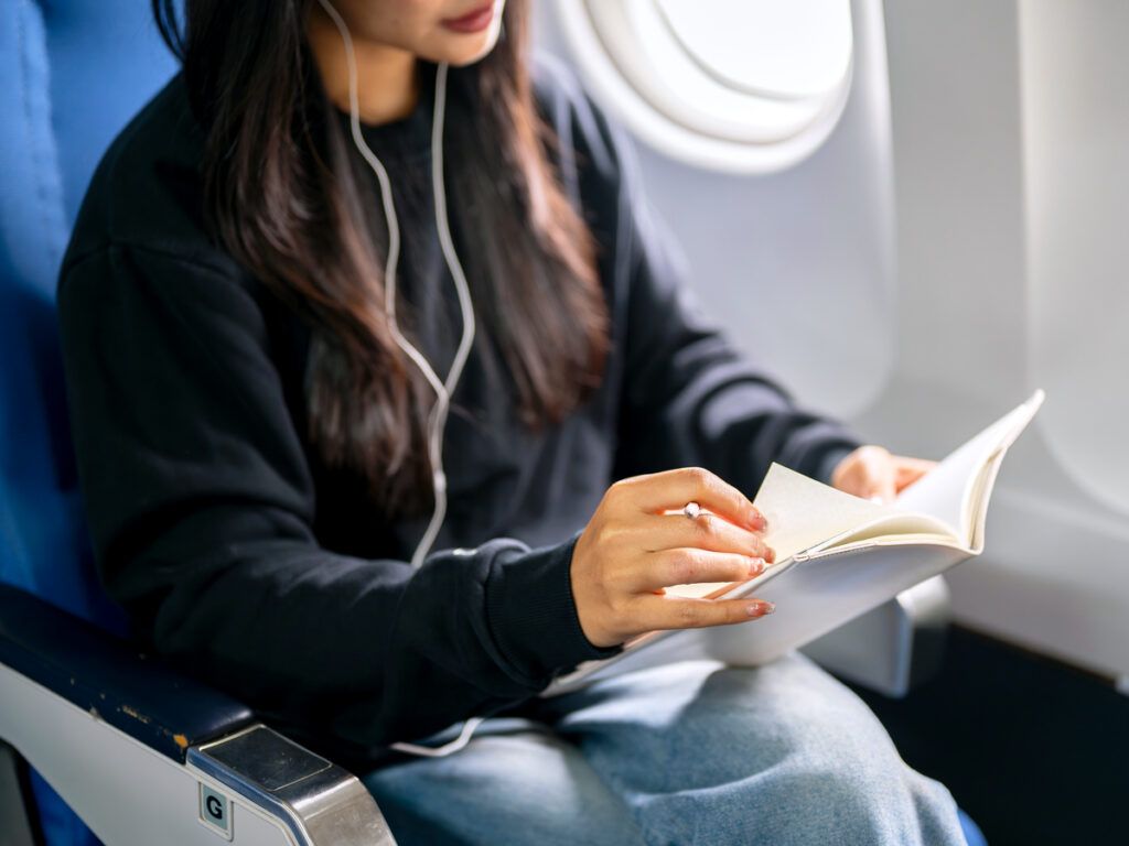 Passenger in window seat reading a book