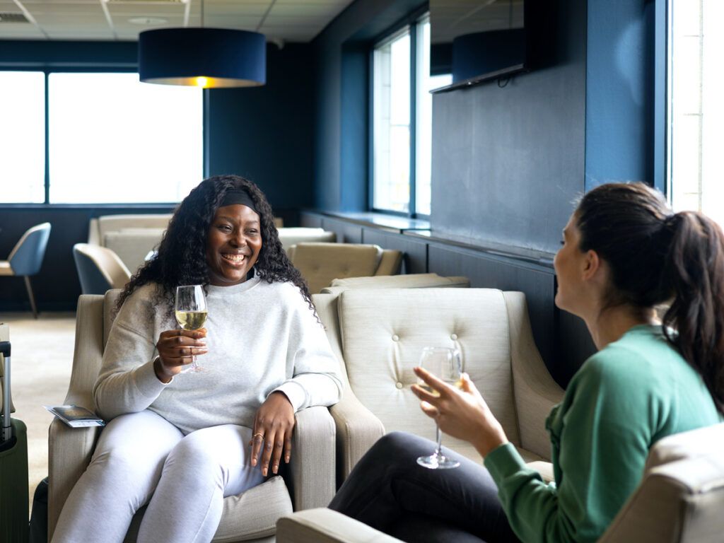Two women sipping wine in an airport lounge