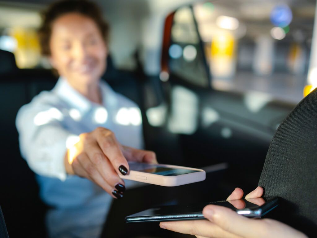 Taxi rider tapping phone to pay