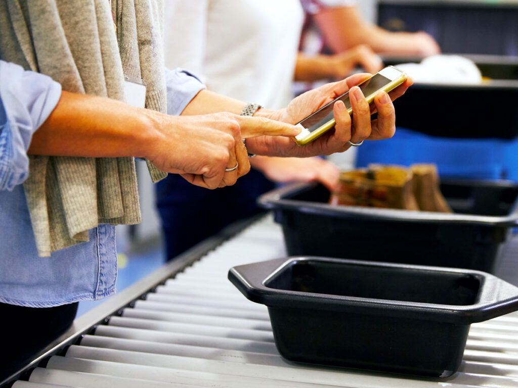 Traveler turning off phone before putting it in bin for security screen