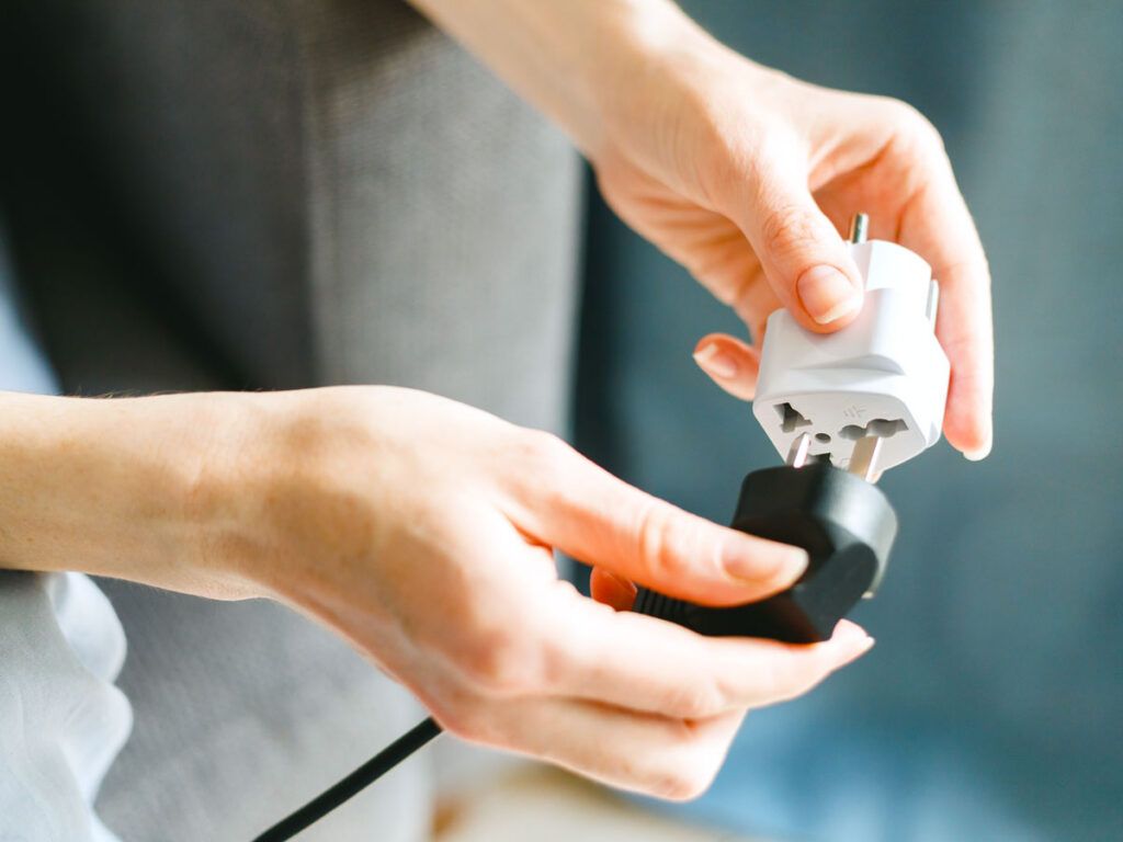 Person plugging device into plug adapter