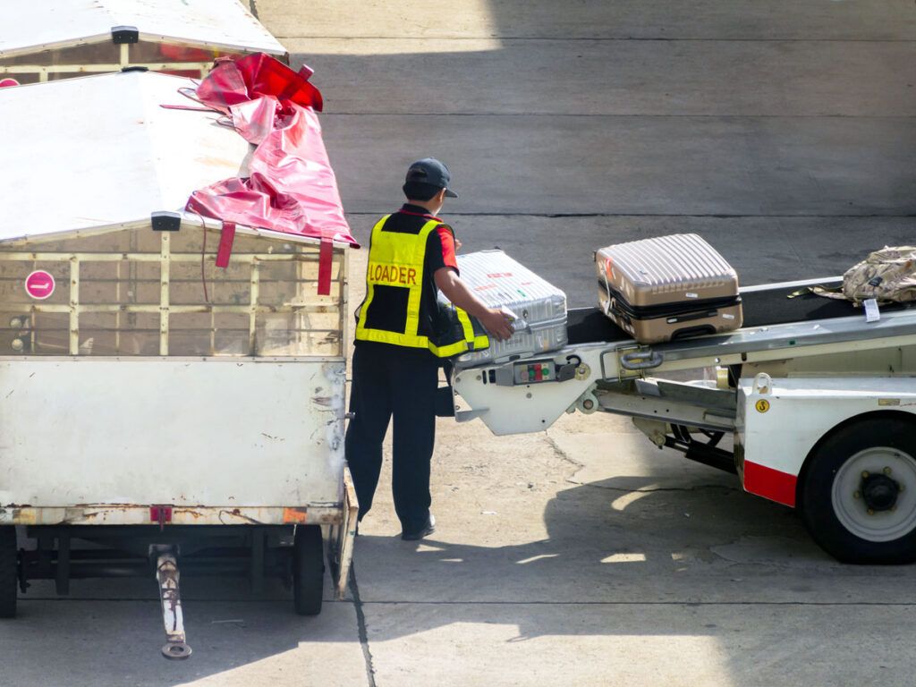 Baggage handler loading luggage onto aircraft