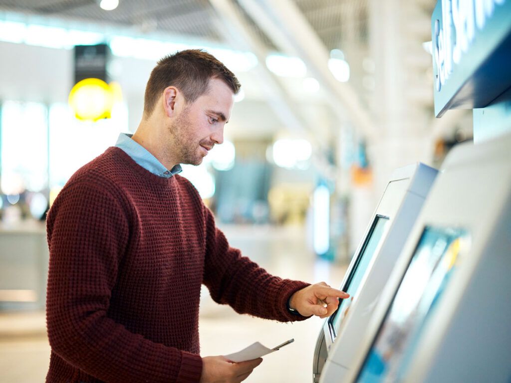 Passenger using self-serve check-in kiosk in airport lobby