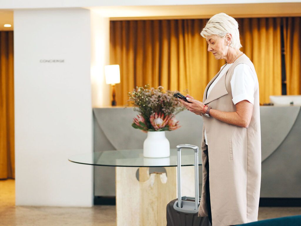 Senior traveler using phone in hotel lobby