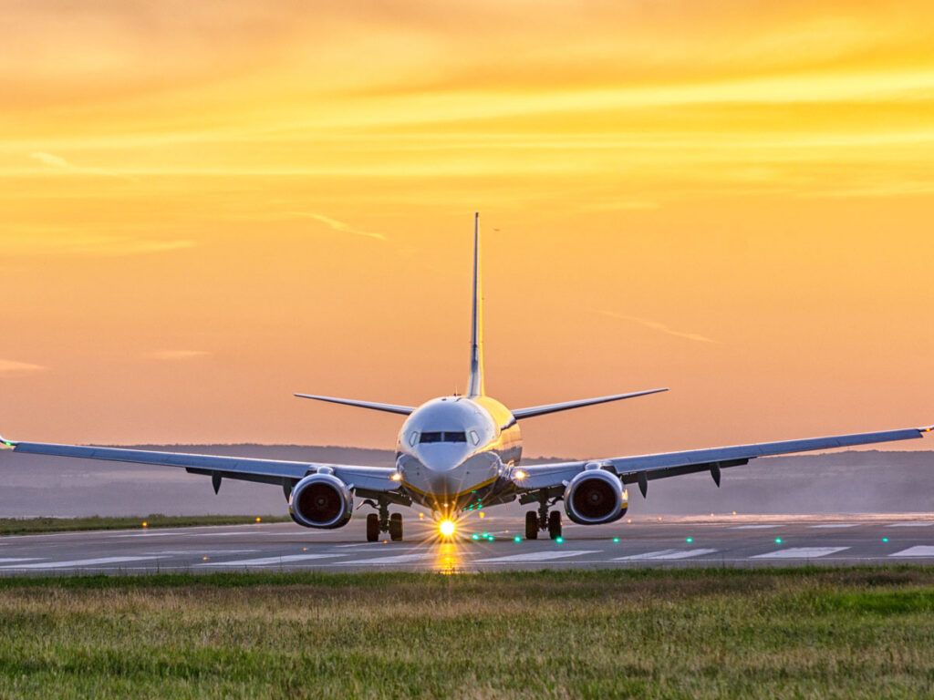 Plane taxiing on runway at sunset
