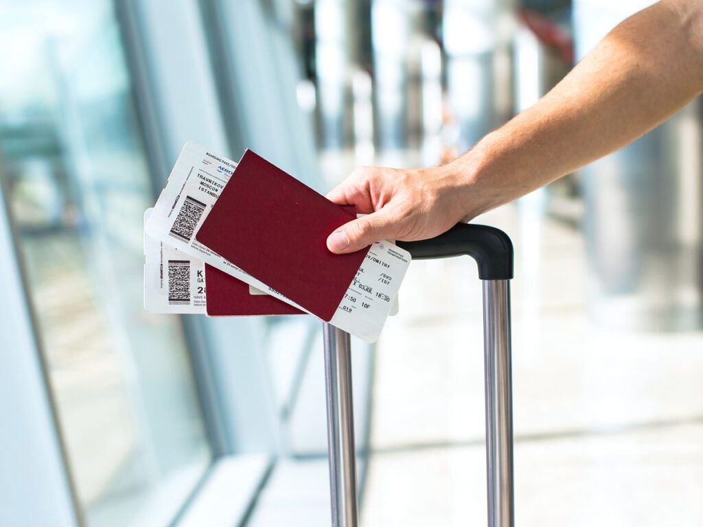 Traveler holding passports and boarding passes on luggage handle