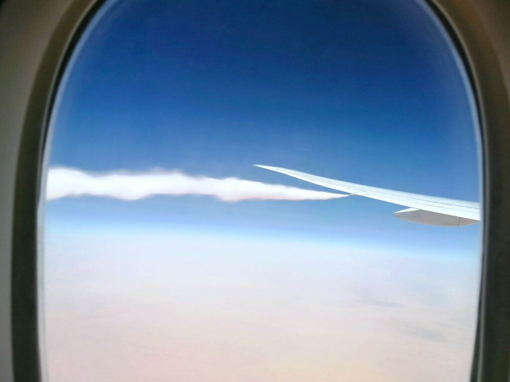 View out airplane window of fuel being jettisoned from wing