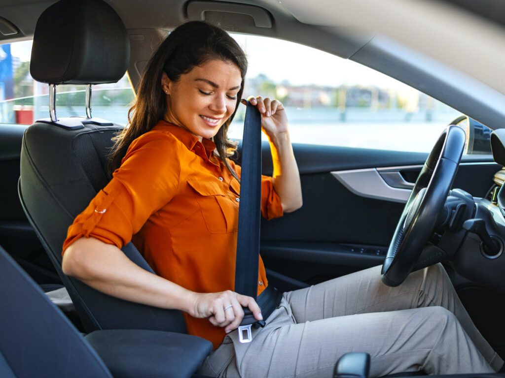 Woman fastening her seat belt in a car