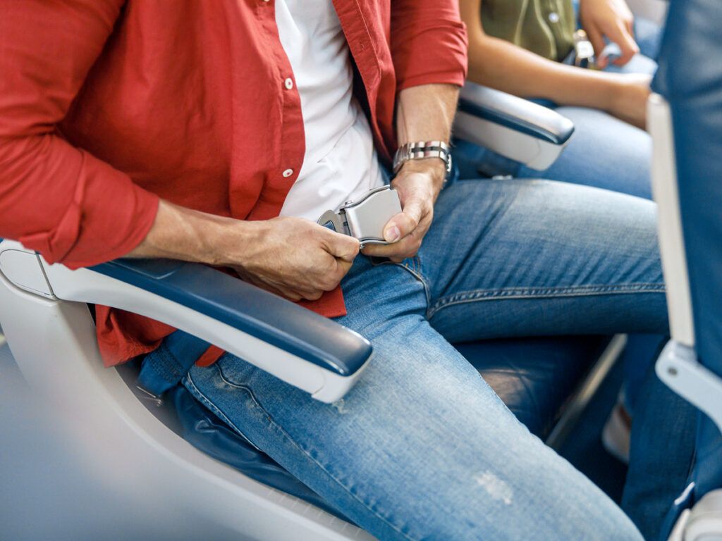 Man adjusting his seat belt on a plane