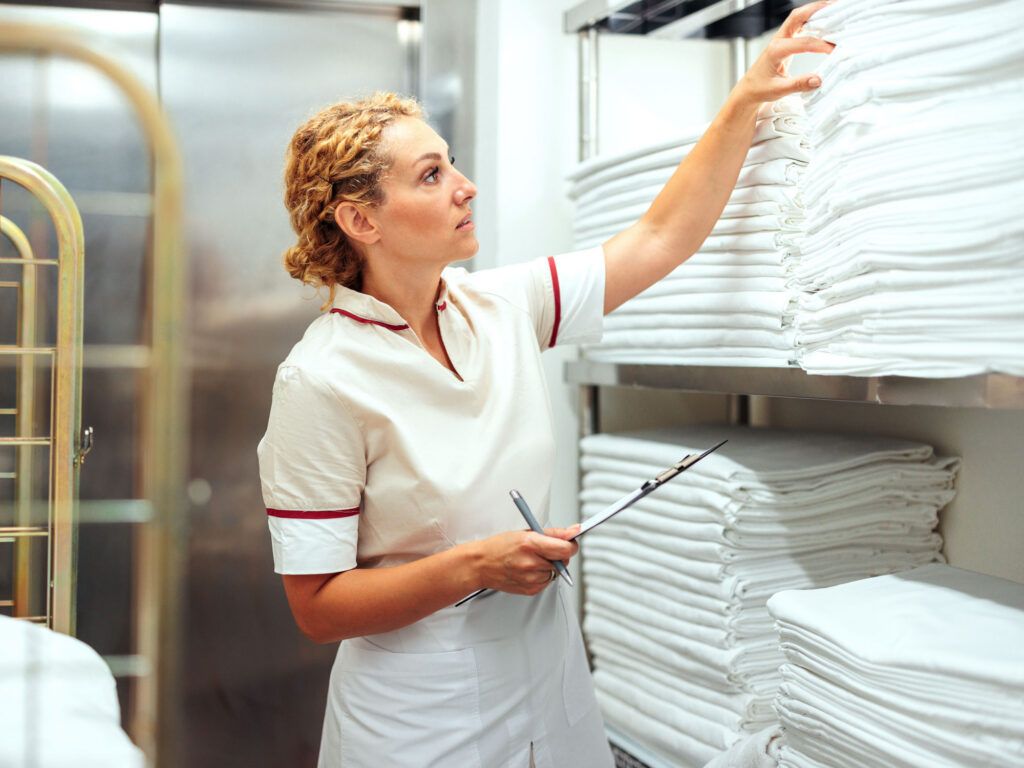 A housekeeper restocks towels in a hotel