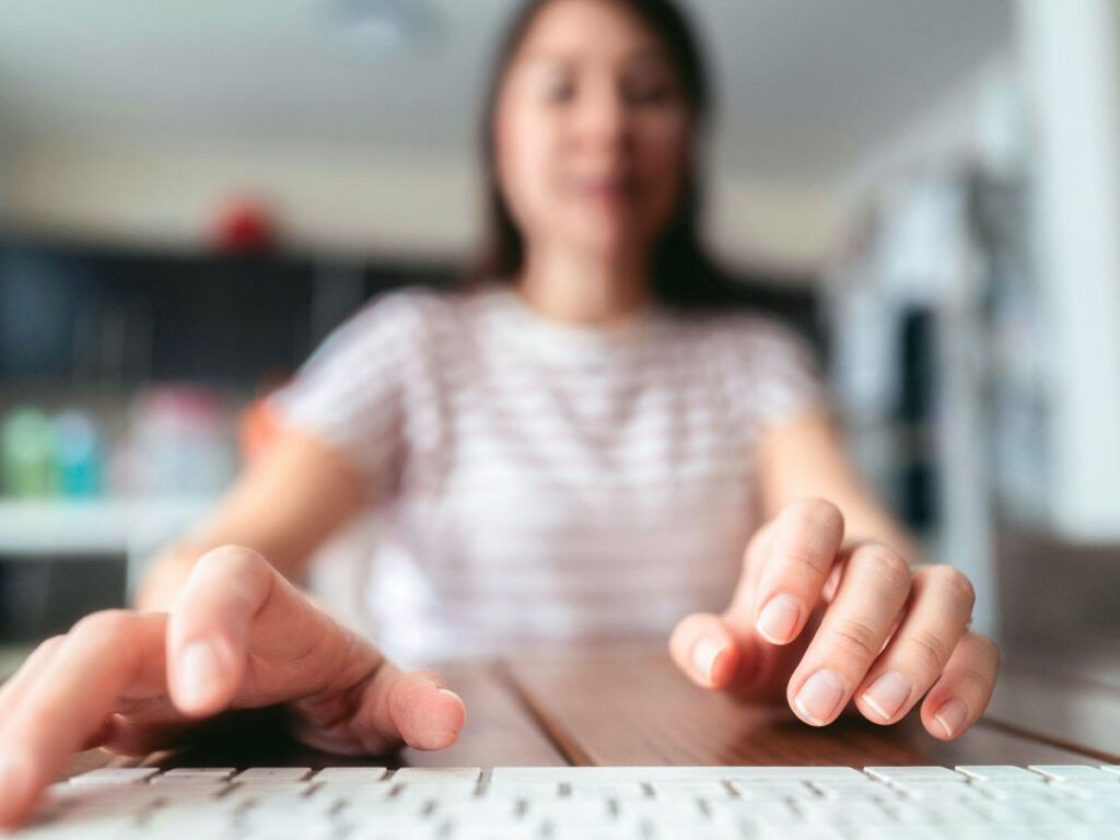 Woman typing on a keyboard at a desk