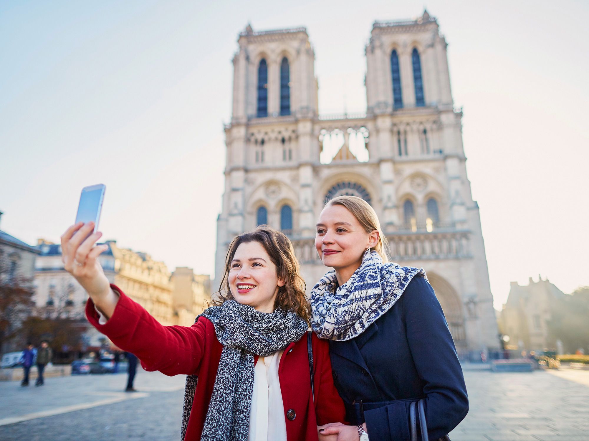 Two women taking a selfie in front of Notre Dame Cathedral in Paris