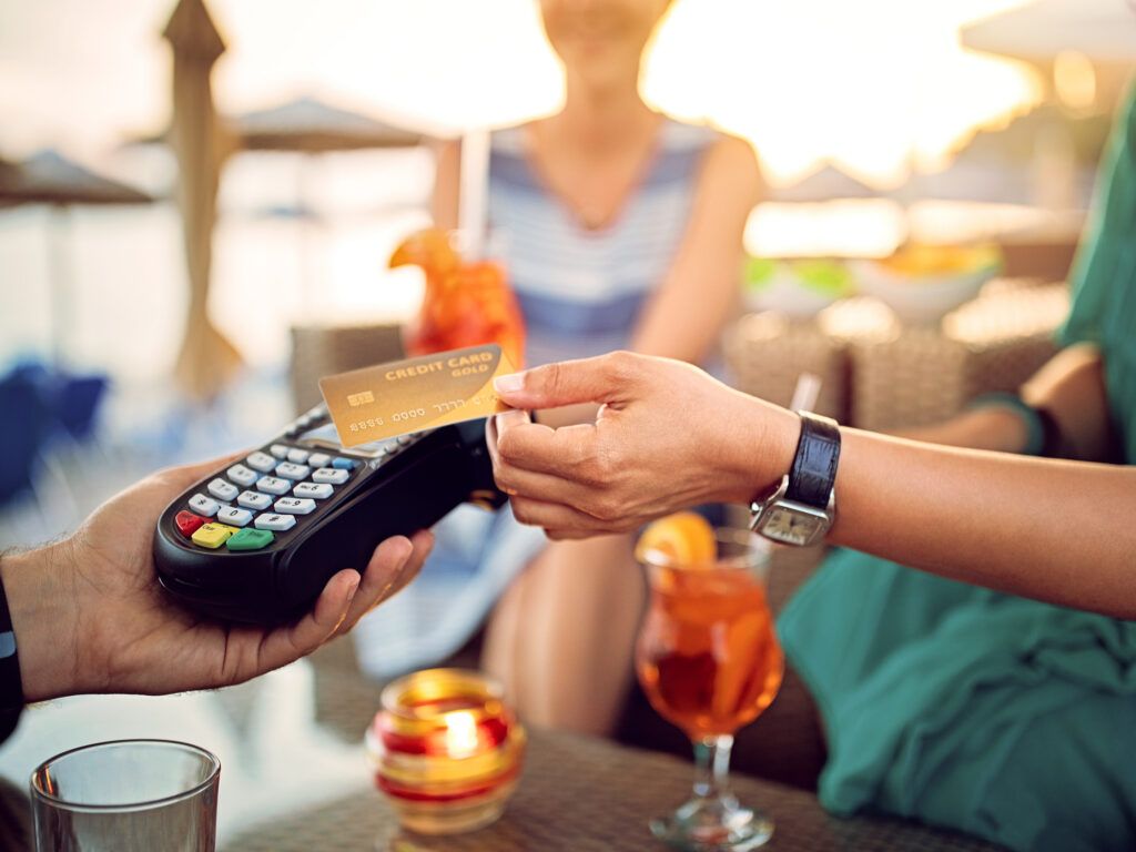 Women paying for cocktails at a beach bar using a contactless credit card
