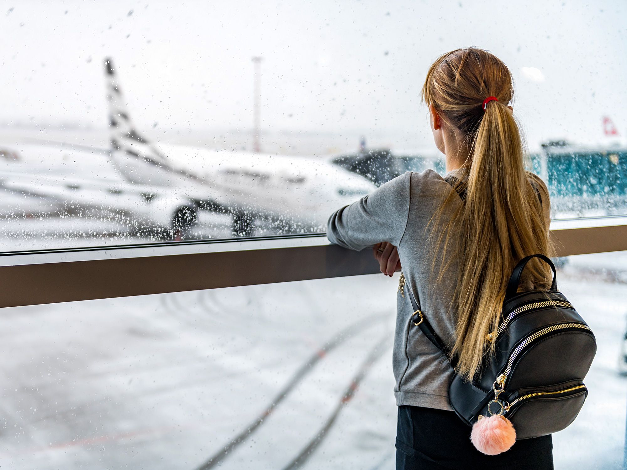 Traveler looking out rainy terminal window