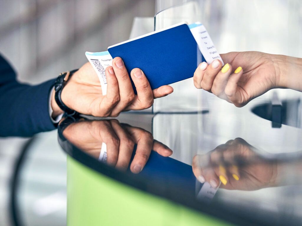 Passport and flight tickets being passed to a member of airport crew
