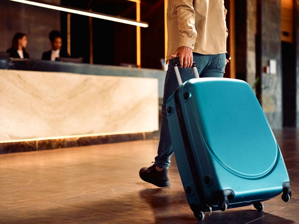 Man rolling a suitcase in a hotel lobby