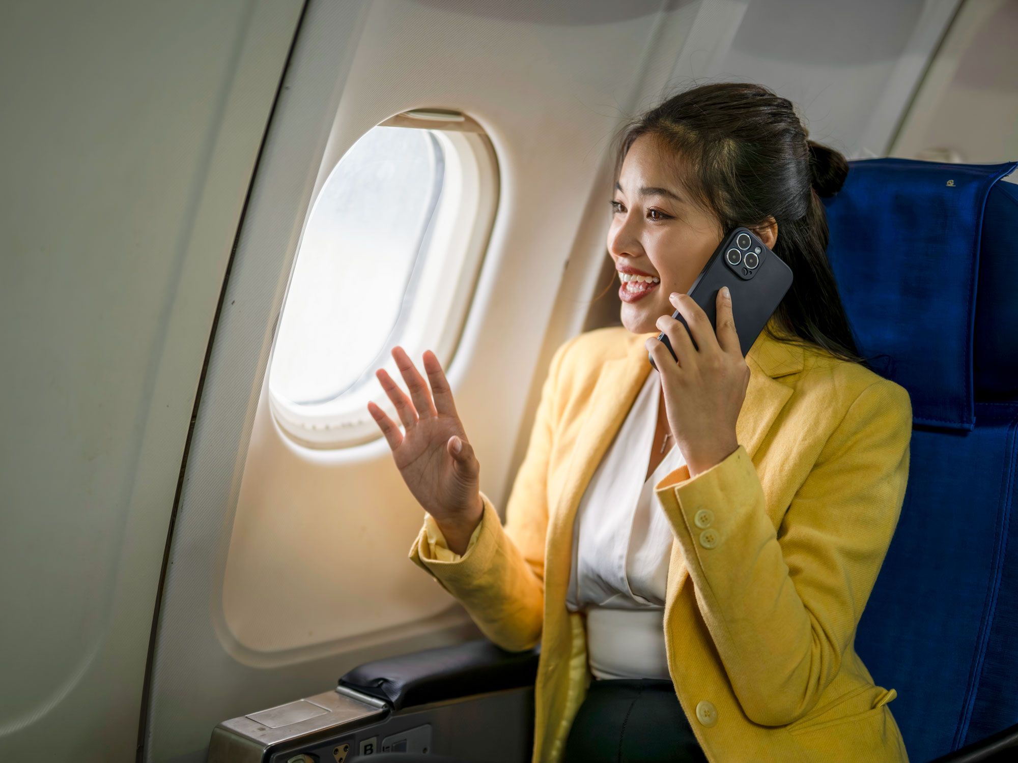 Passenger talking on phone in airplane seat