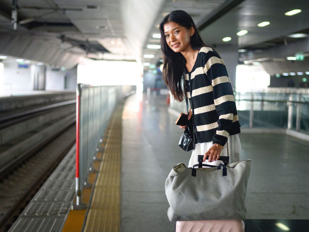 Woman carrying a tote bag near a train platform