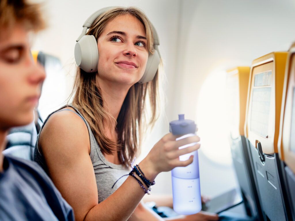 Woman drinks from her water bottle during a flight