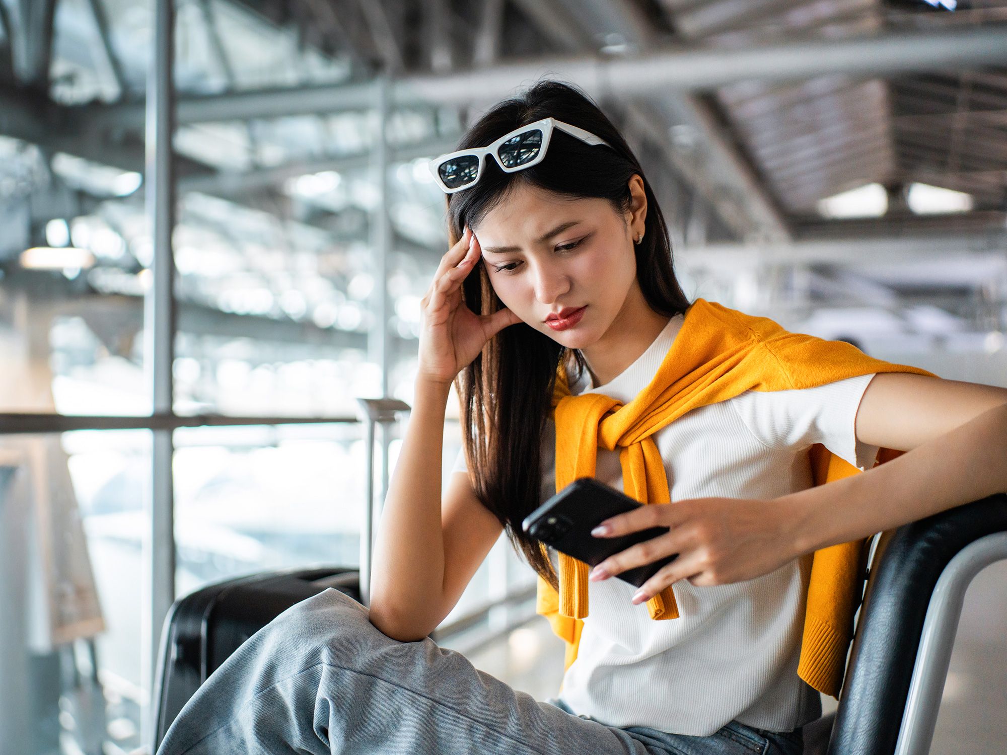 Traveler sitting in airport terminal looking at phone