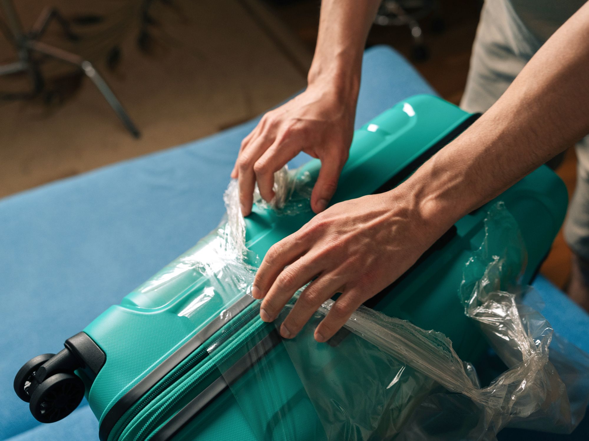 Person removing shrink wrap from luggage