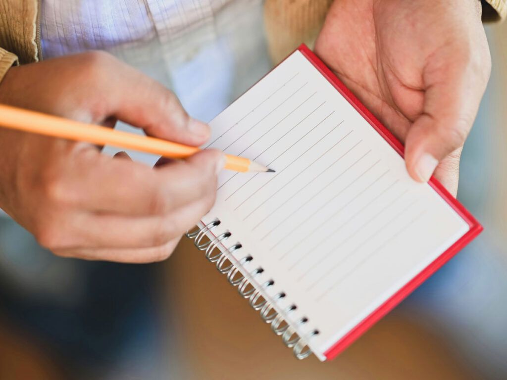 Man writing with a pencil in a notebook