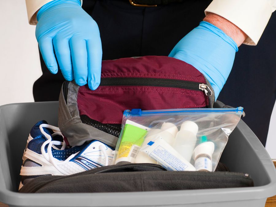 TSA agent searches through luggage at an airport security checkpoint